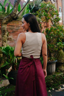 Woman in beige top and Hemp Wrap mulberry maroon wrap skirt standing in a garden setting.