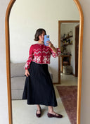 Person taking a mirror selfie wearing a red floral top and black Wildalaya wrap skirt.