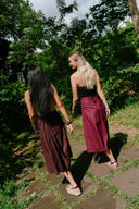 Two women walking wearing Wildalaya wrap skirts on a stone path through a lush green forest.