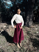 Woman in a white top and Wildalaya Mulberry Hemp wrap skirt standing in a forest setting