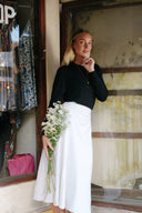 Woman holding flowers standing in front of a store wearing Wildalaya Wrap Moonstone Skirt