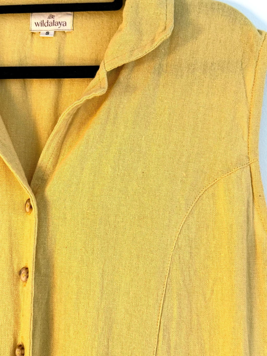 Widalaya Hemp Yellow sleeveless shirt with a brand label on a light blue background