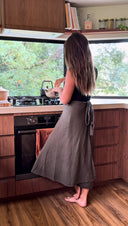 Woman in a kitchen looking into an oven wearing Wildalaya wrap mossy grove cotton skirt